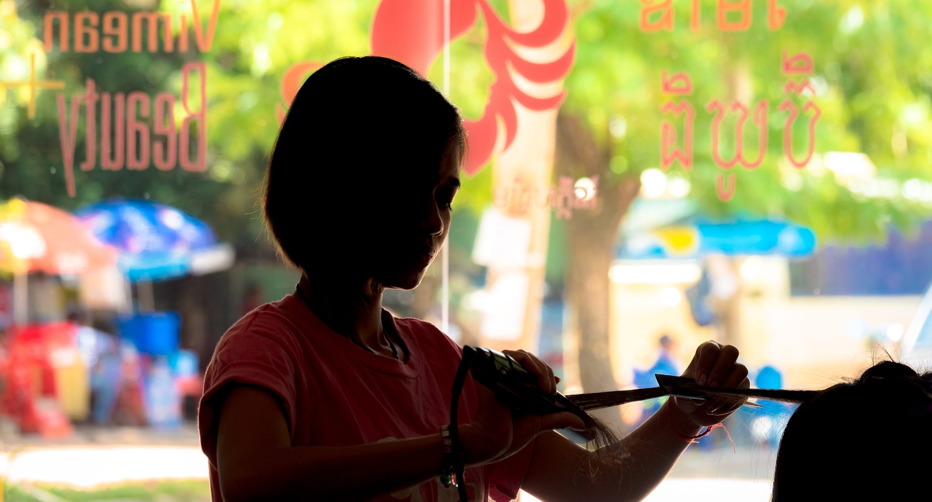 Silhouette of student cutting hair in front of beauty plus window