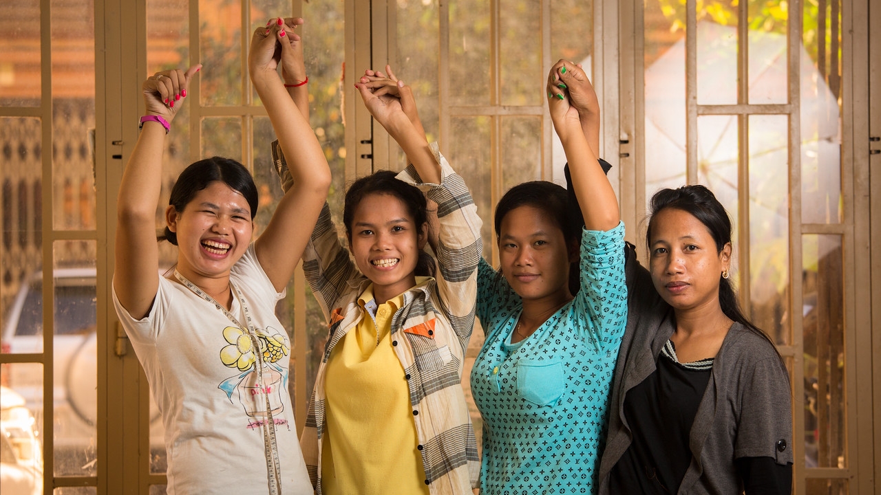 Four Beauty Plus Students with their hands in the air